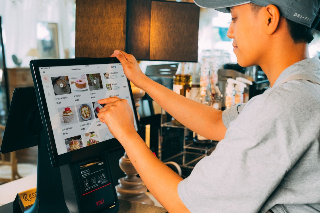 Kasir menggunakan aplikasi POS modern di restoran